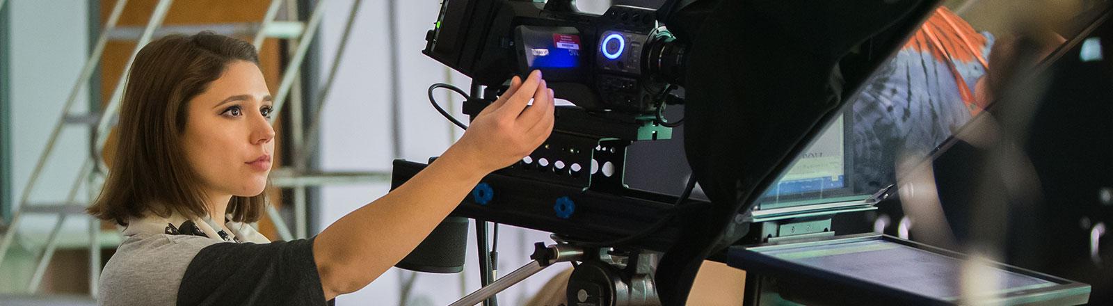 Journalism student adjusting camera in video studio
